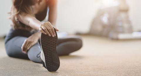 image of a person in workout clothes sitting on the floor doing a hurdler's stretch