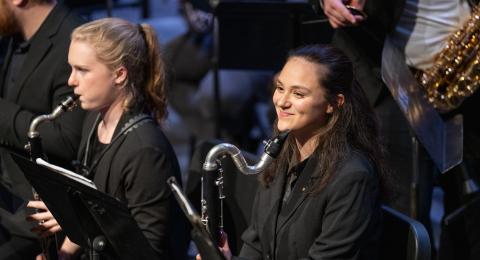 Wind Symphony bass clarinet player smiles next to alto clarinetist playing instrument