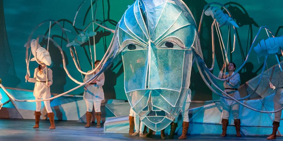 Theater students on stage with a giant mask