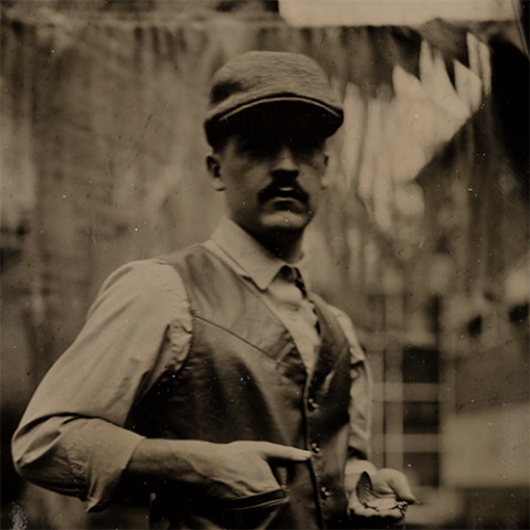 Sepia portrait of a mustachoed man wearing a hat