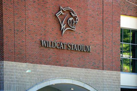 Close up view of silver Cat Head logo and Wildcat Stadium signage on brick wall outside stadium