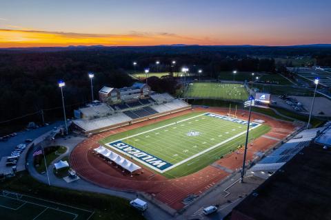 Aerial view of empty Wildcat Stadium with the lights on at sunset.