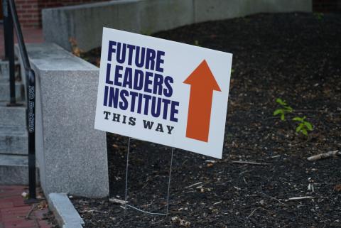 A sign with blue writing and an orange arrow showing the way to the Future Leaders Institute