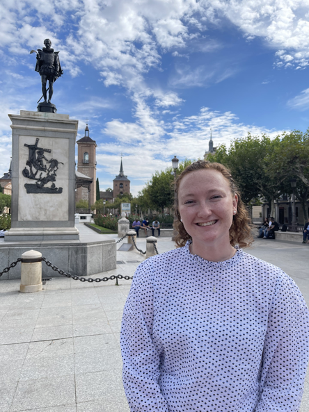 Kat Heaney, EdD student, standing and smiling in front of a monument. 